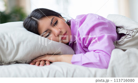 Woman resting on bed in comfortable home 113716080
