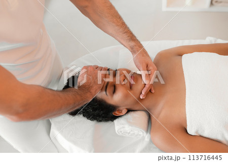 Male masseur giving face massage to woman Male masseur giving face massage to woman 113716445