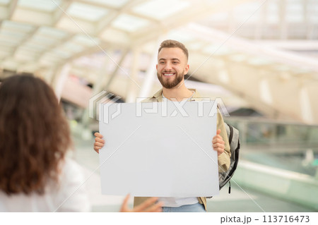Man with blank name board placard meeting his wife at airport after arrival 113716473