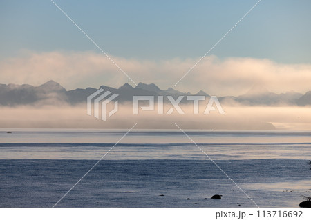 Misty lake framed by mountains, creating a serene natural landscape Misty lake framed by mountains, creating a serene natural landscape 113716692