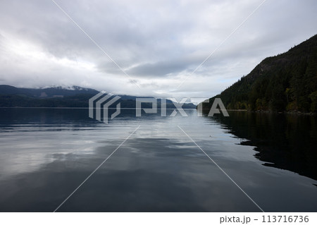 Majestic clouds hover over a vast lake framed by towering mountains Majestic clouds hover over a vast lake framed by towering mountains 113716736
