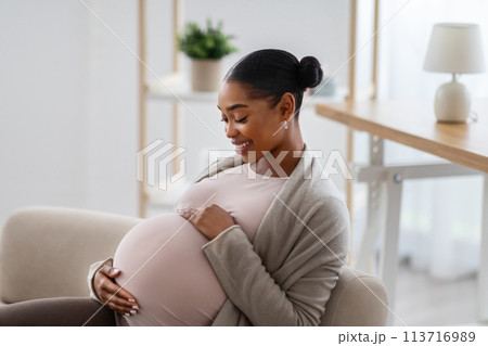 Side view of african american expecting woman touching her big belly 113716989