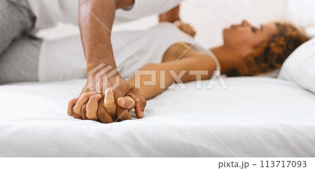 Close-up of couple holding hands on bed 113717093