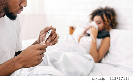 Sick woman in bed, man checking temperature on thermometer 113717115