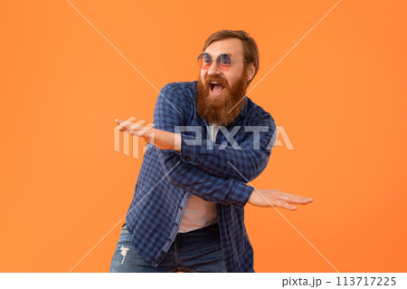 Funny joyful redhaired man with beard in sunglasses dancing, studio 113717225