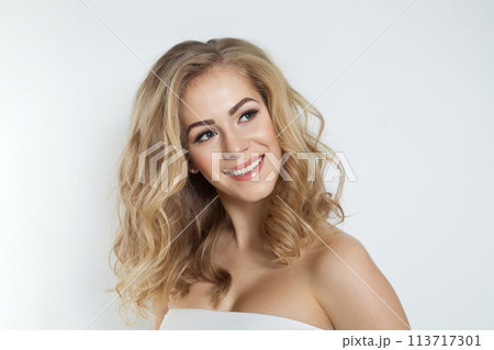 Beautiful blonde woman with healthy clean skin and long wavy hair looking up on white background 113717301