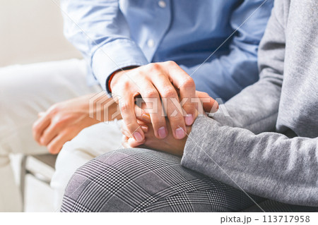 Closeup of unrecognizable man comforting his wife, holding her hands 113717958
