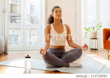 lady practices yoga meditating and breathing in lotus position indoors lady practices yoga meditating and breathing in lotus position indoors 113718092