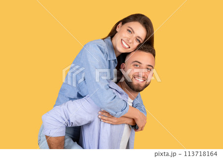 Woman piggybacking on man's back on yellow Woman piggybacking on man's back on yellow 113718164