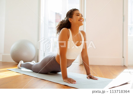 Motivated athletic lady engages in morning gymnastics bending upward indoor Motivated athletic lady engages in morning gymnastics bending upward indoor 113718364