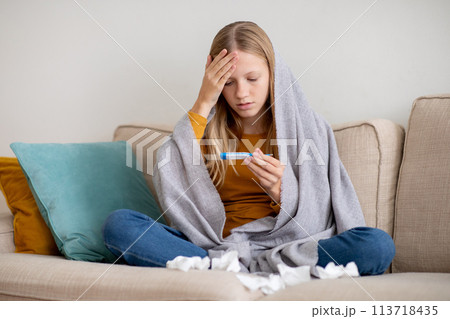 Teen Girl Checking Temperature With Thermometer Indoors 113718435