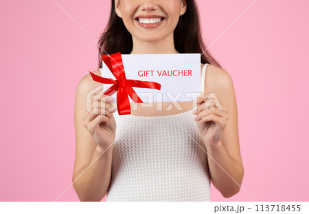 Lady holding a gift voucher with a bow, cropped Lady holding a gift voucher with a bow, cropped 113718455