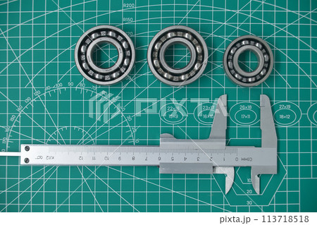 Measure caliper and roller bearings on cutting mat Measure caliper and roller bearings on cutting mat 113718518
