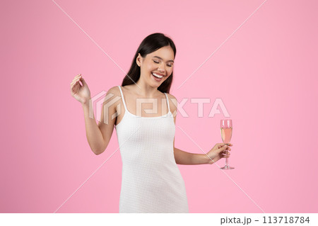 Young lady holding a champagne flute cheerfully Young lady holding a champagne flute cheerfully 113718784