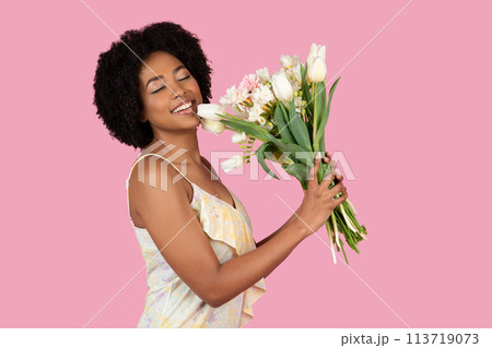 Woman enjoying bouquet of flowers on pink background 113719073