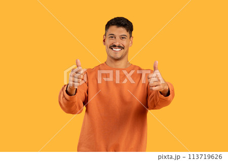 Smiling guy with thumbs up on orange backdrop Smiling guy with thumbs up on orange backdrop 113719626