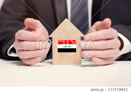 Businessman hand holding wooden home model with Iraqi flag. insurance and property concepts 113719652
