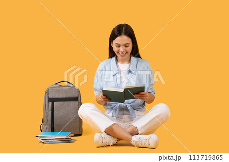Concentrated woman reading a book on yellow background Concentrated woman reading a book on yellow background 113719865