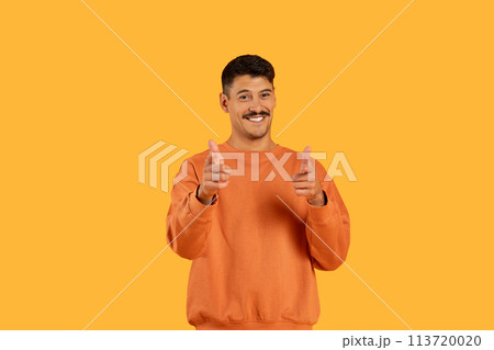 Guy gives thumbs up with a smile on orange 113720020