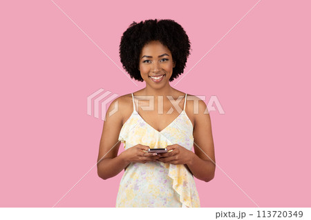 Young African American woman using smartphone on pink Young African American woman using smartphone on pink 113720349