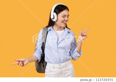 Happy young woman wearing headphones and dancing Happy young woman wearing headphones and dancing 113720355