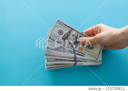 Hands holding dollars on a blue background with space for text 113720812