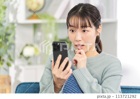 スマートフォンを見て驚く女性 スマートフォンを見て驚く女性 113721292