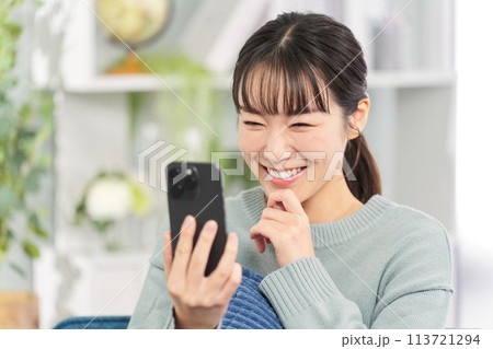 ソファに座ってスマートフォンを見る女性 ソファに座ってスマートフォンを見る女性 113721294