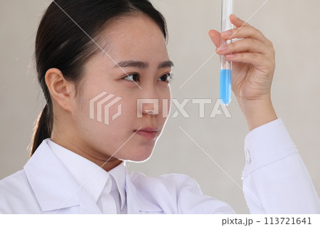 真剣な表情で試験管を見る白衣の女性 113721641
