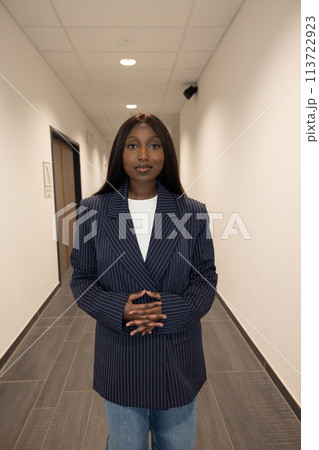 Confident Professional in Pinstripe Blazer Standing in Office Hallway 113722923