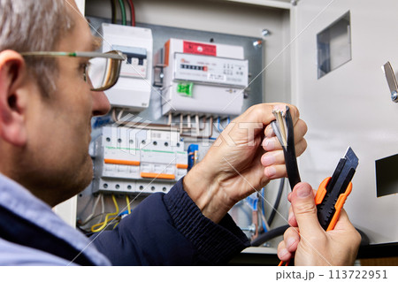 Cutting over sheath of power cable using retractable utility knife, electrician cuts outer sheath of high-voltage cable. Cutting over sheath of power cable using retractable utility knife, electrician cuts outer sheath of high-voltage cable. 113722951