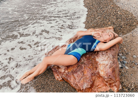 Woman summer travel sea. Happy tourist in blue bikini enjoy taking picture outdoors for memories. Woman traveler posing on the beach surrounded by volcanic mountains, sharing travel adventure journey Woman summer travel sea. Happy tourist in blue bikini enjoy taking picture outdoors for memories. Woman traveler posing on the beach surrounded by volcanic mountains, sharing travel adventure journey 113723060