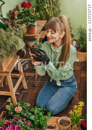 Young Woman Planting Flowers at City Balcony 113723717