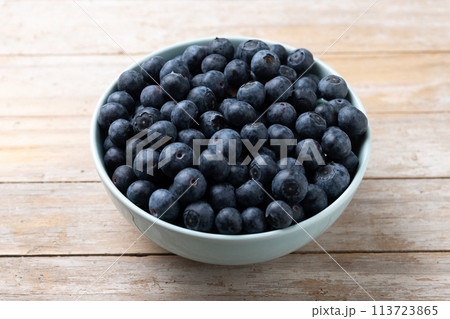 Blueberries in green bowl on wooden table 113723865
