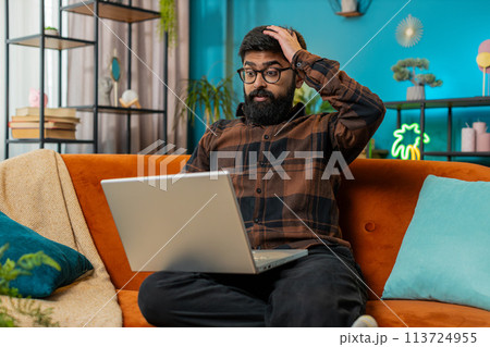 Amazed Indian man use laptop computer, receive good news message shocked by victory, celebrate win 113724955