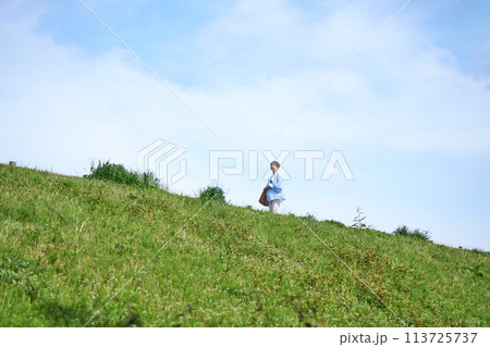 土手を歩く女性 113725737