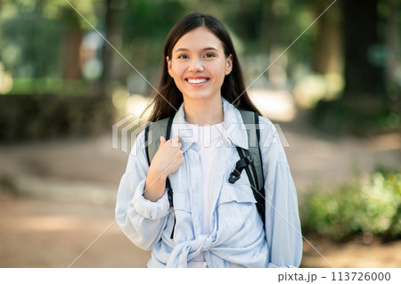 Smiling young woman with long dark hair wearing a white shirt. 113726000