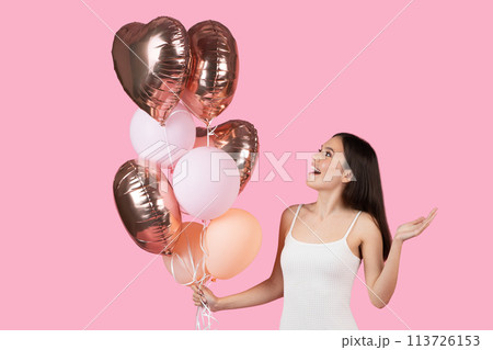 Lady gestures with heart-shaped balloons on pink background Lady gestures with heart-shaped balloons on pink background 113726153
