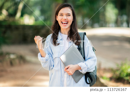Enthusiastic young woman celebrating success with a fist pump 113726167