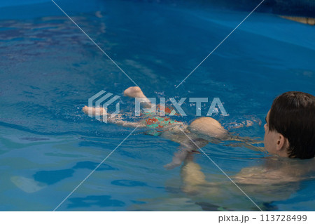 Swim coach teach a baby for diving under water. Swimming lessons for newborns. Swim coach teach a baby for diving under water. Swimming lessons for newborns. 113728499