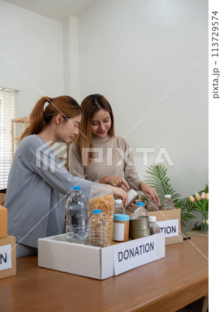 Donation and two woman volunteer asian of happy packing food in box at home. Charity 113729574