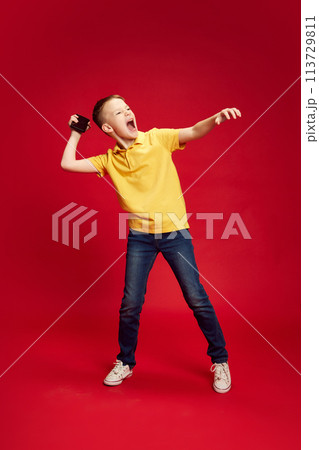 Angry boy, upset teenager want to dump his cell phone against red studio background. Game failure. Bad luck. 113729811