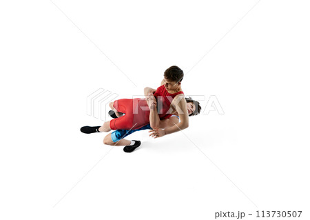 Young men, athletes compete fiercely in wrestling match, displaying determination and skills isolated on white background 113730507