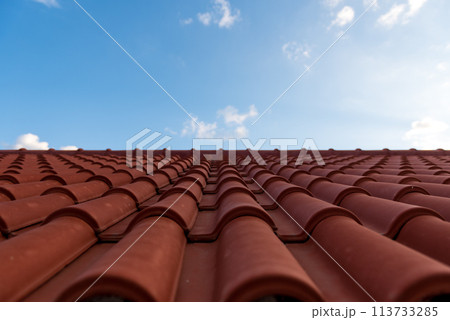 Red tile roof under blue sky. One part is a roof and the other is a pure blue sky. Red tile roof under blue sky. One part is a roof and the other is a pure blue sky. 113733285