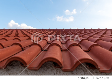 Red tile roof under blue sky. One part is a roof and the other is a pure blue sky. Red tile roof under blue sky. One part is a roof and the other is a pure blue sky. 113733286