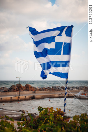 Greek flag on wall near sea on Crete island 113733291