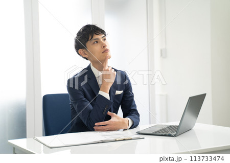 ノートパソコン入力作業中に疑問に思う男性ビジネスマン ノートパソコン入力作業中に疑問に思う男性ビジネスマン 113733474