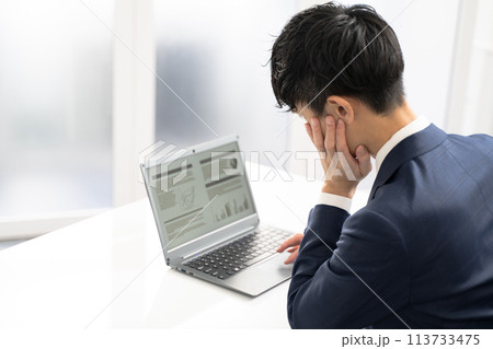 ノートパソコンで資料作成時に悩む男性ビジネスマン ノートパソコンで資料作成時に悩む男性ビジネスマン 113733475