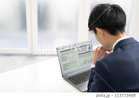 ノートパソコンで資料作成時に悩む男性ビジネスマン ノートパソコンで資料作成時に悩む男性ビジネスマン 113733480