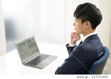 ノートパソコンで資料作成時に悩む男性ビジネスマン 113733481